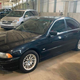 A black BMW 530i with blacked out windows in a warehouse